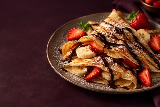 Sweet crepes topped with strawberries, banana and chocolate